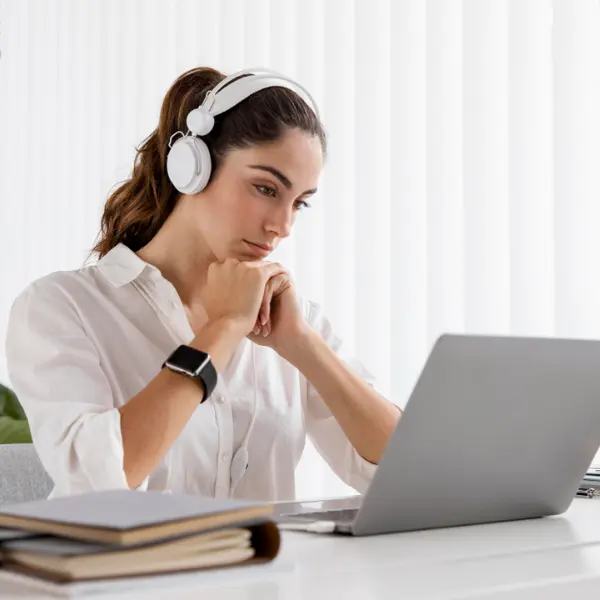 une femme qui regarde son ecran d'ordinateur portable avec un casque sur les oreilles