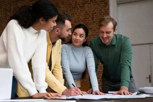 4 personnes qui regarde des documents sur une table pour finaliser un projet