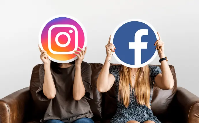 Deux. Femmes sur un canapé une à gauche et une à droite toutes les deux, tenant une pancarte, celle de gauche avec le logo Instagram, celle de droite avec le logo Facebook.