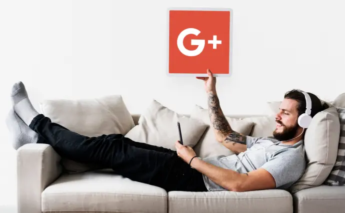 Un homme allongé dans un canapé, tenant dans sa main droite, une pancarte avec le logo Google dessus