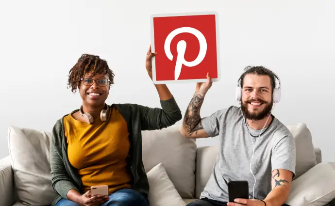2 personnes assis sur un canapé qqqui tienne la même pancarte avec le logo de Pinterest dessus