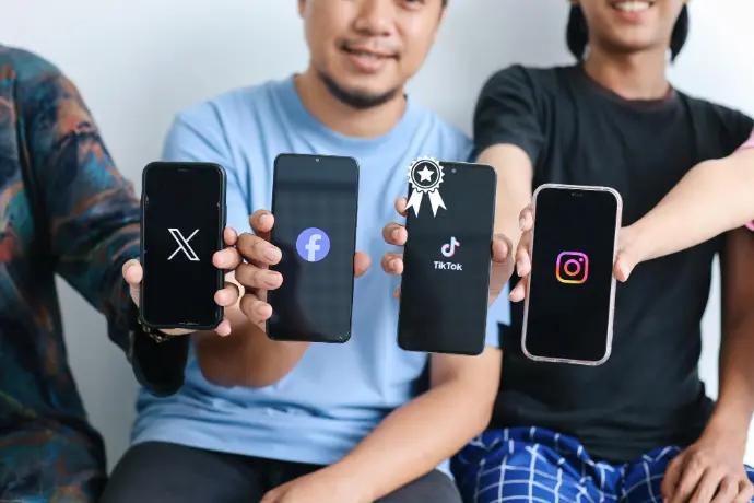 Quatre. Personnes montrant leur téléphone avec sur leur écran, chacun un logo, deux, Twitter, Facebook, TikTok Instagram.