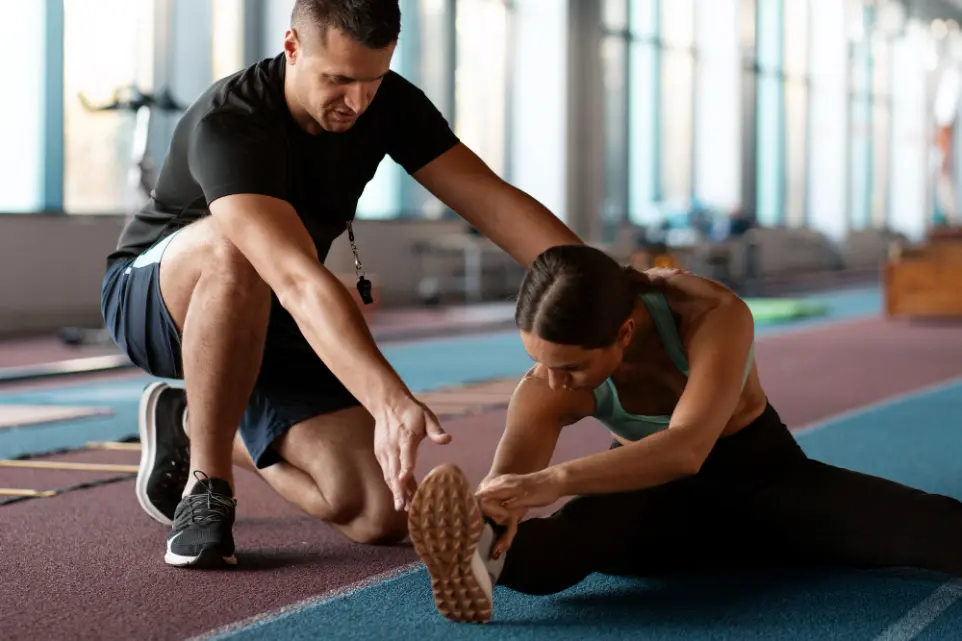 Un coach sportif qui est d'une de ses élèves à tirer les jambes dans une Salle De Sport 🏋️
